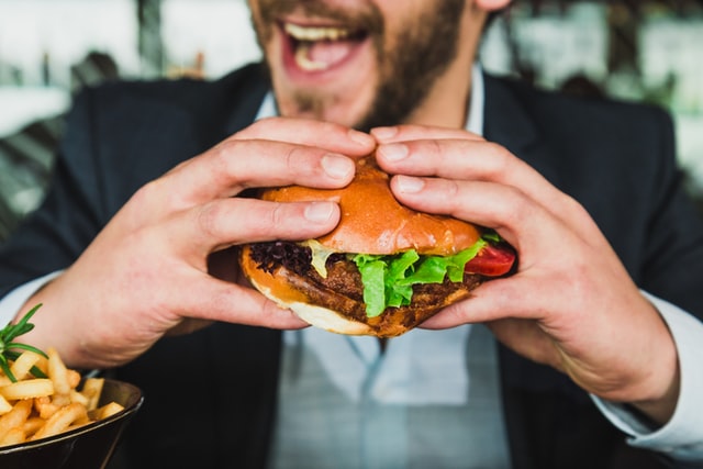 ハンバーガーを食べている男性